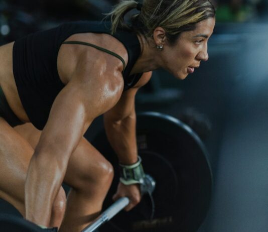 Stretching Barely Prevents Injuries. Strength Training Cuts Them by Two Thirds. A woman lifting a loaded barbell in a gym