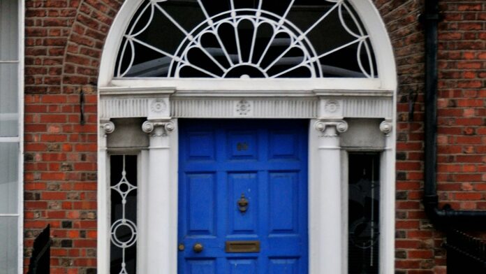 A woman walking past a blue door on a brick building