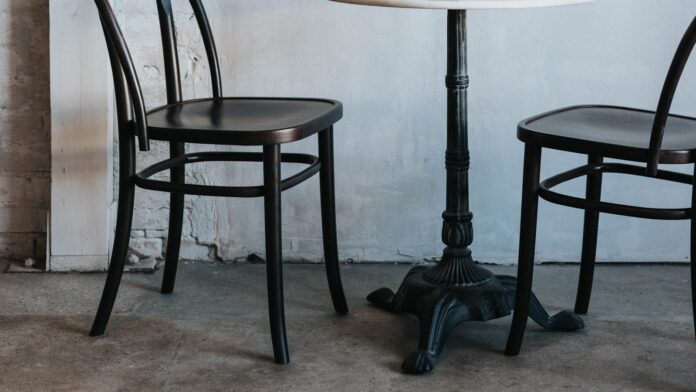 Two chairs and a small table against a white wall