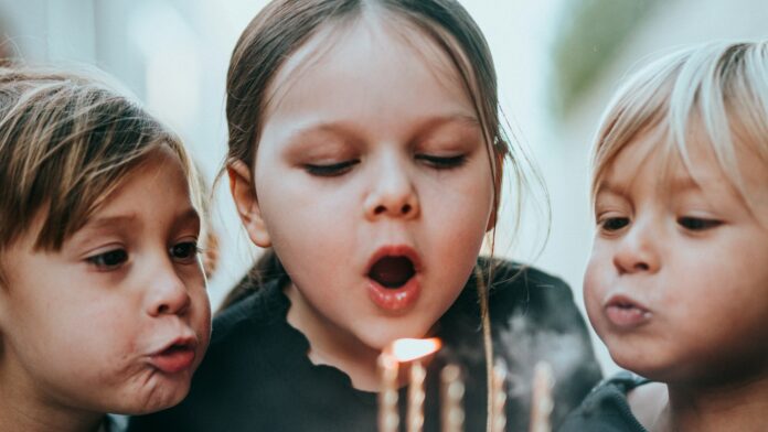 children-birthday-candles Two young children blowing out candles on a birthday cake