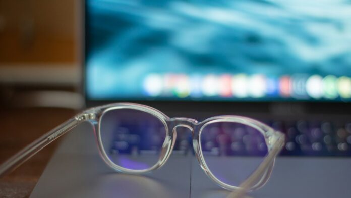 A pair of silver-framed eyeglasses resting on a white table