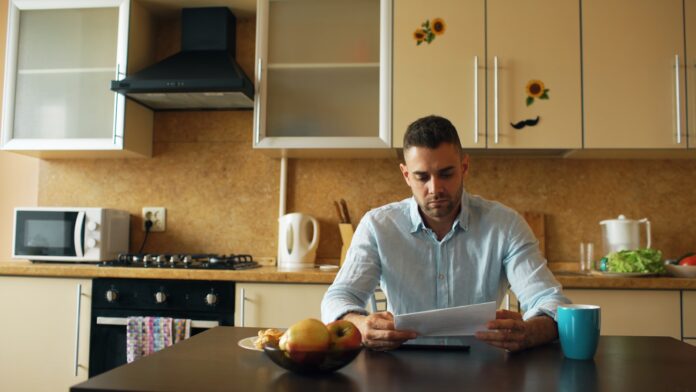 A man reading a document at a kitchen table