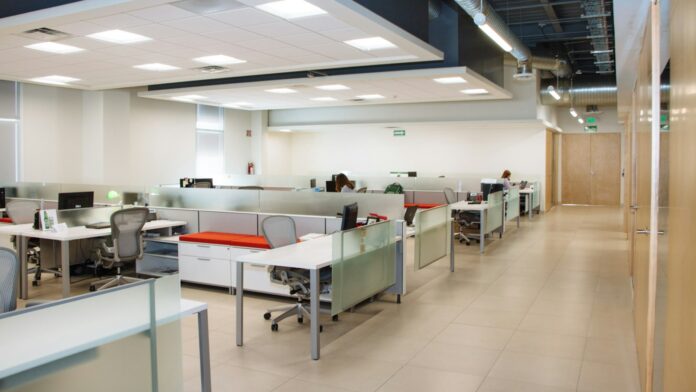 An open plan office with long rows of white desks