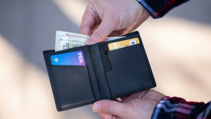 A black leather bifold wallet held open in a person's hand