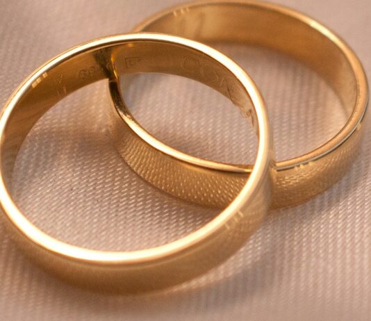 The 50% Divorce Rate Was True for About One Year. You Can Name It. Two interlocking gold wedding bands on a textured surface