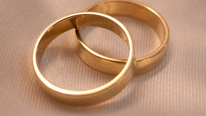Two interlocking gold wedding bands on a textured surface